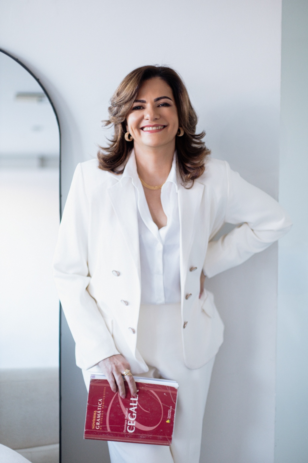 Professora Simone Nogueira em pé com um livro de gramática