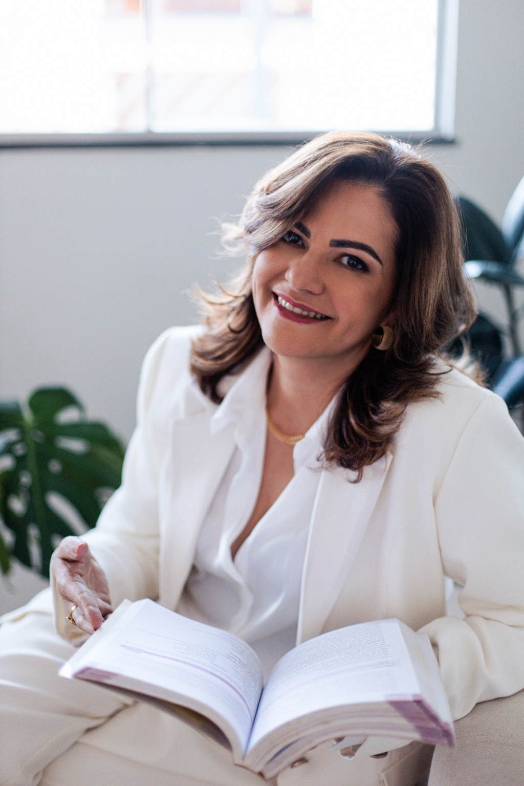Simone Nogueira sentada com um livro aberto